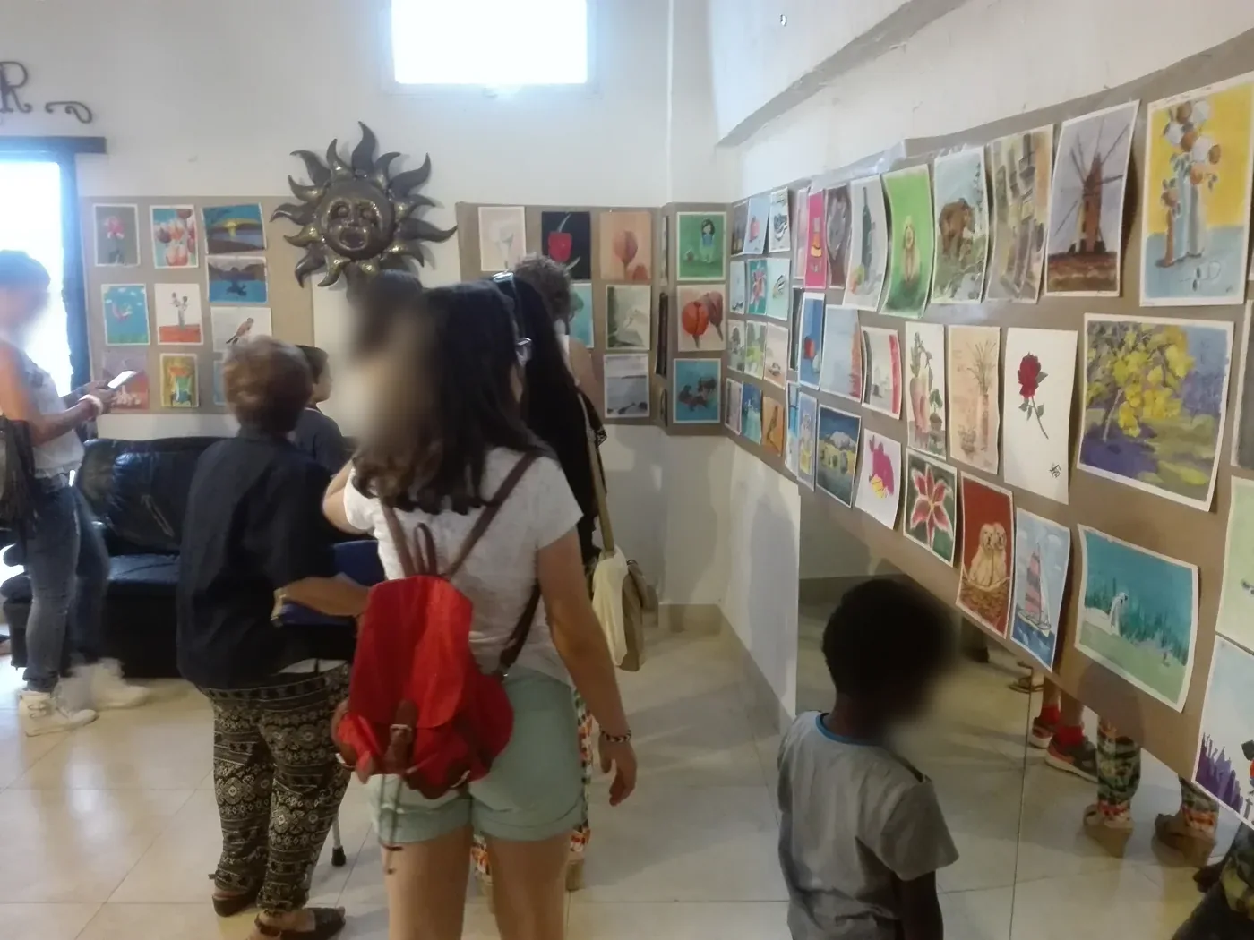 Visitantes ante una pared llena de obras de alumnos