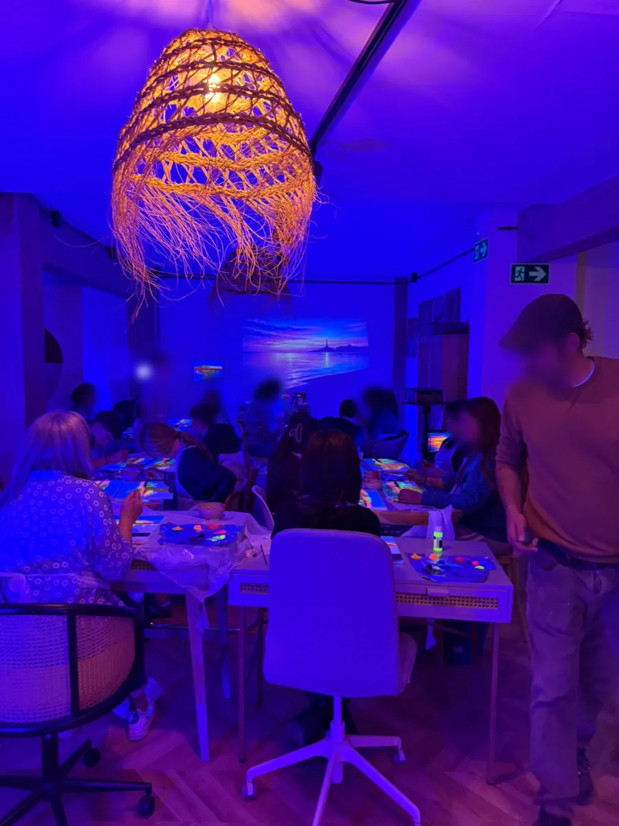 Sala llena de participantes en un taller de pintura con neón